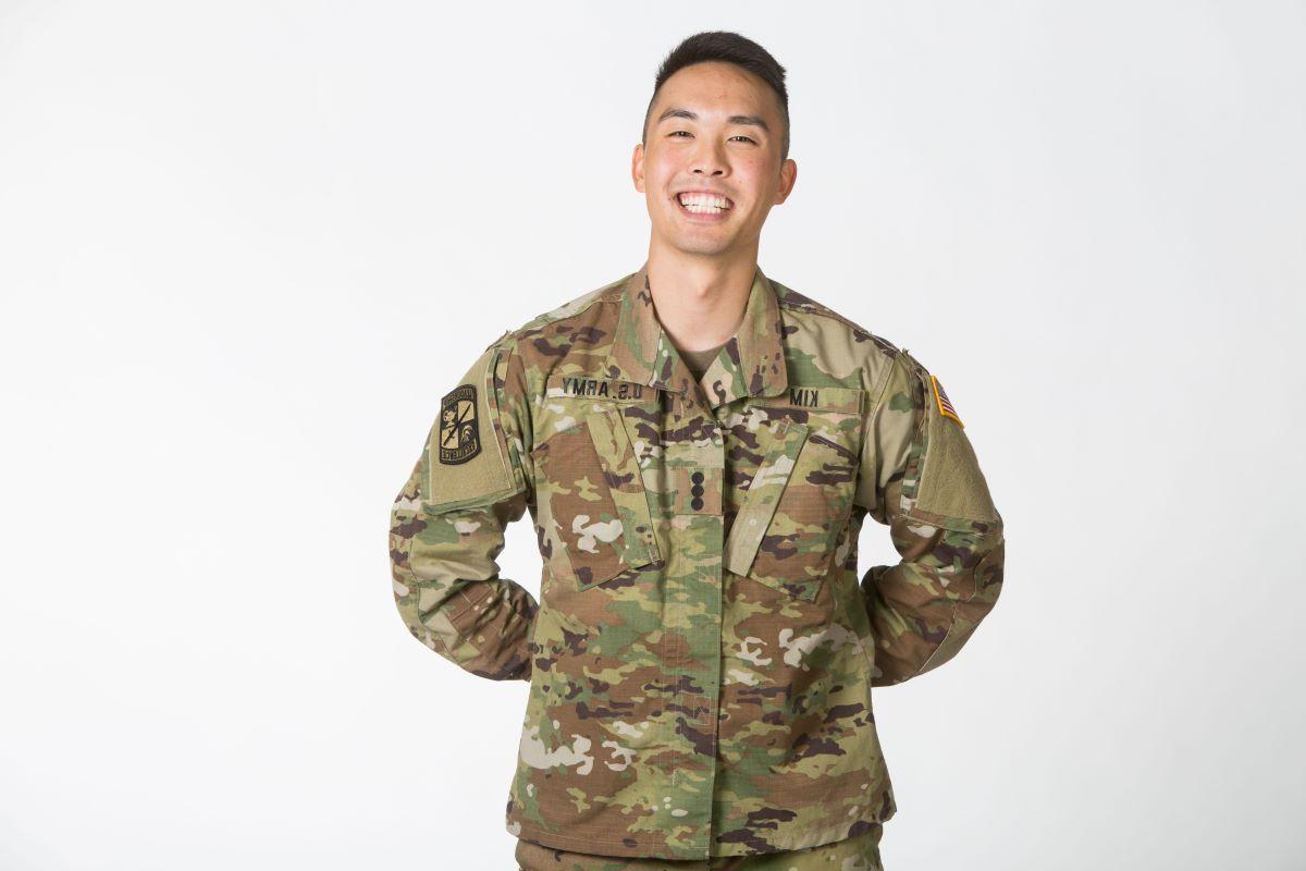 man in military fatigues stands with his hands behind his back